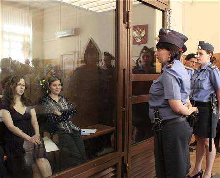 Members of the female punk band "Pussy Riot" sit in the defendant's cell before a court hearing in Moscow